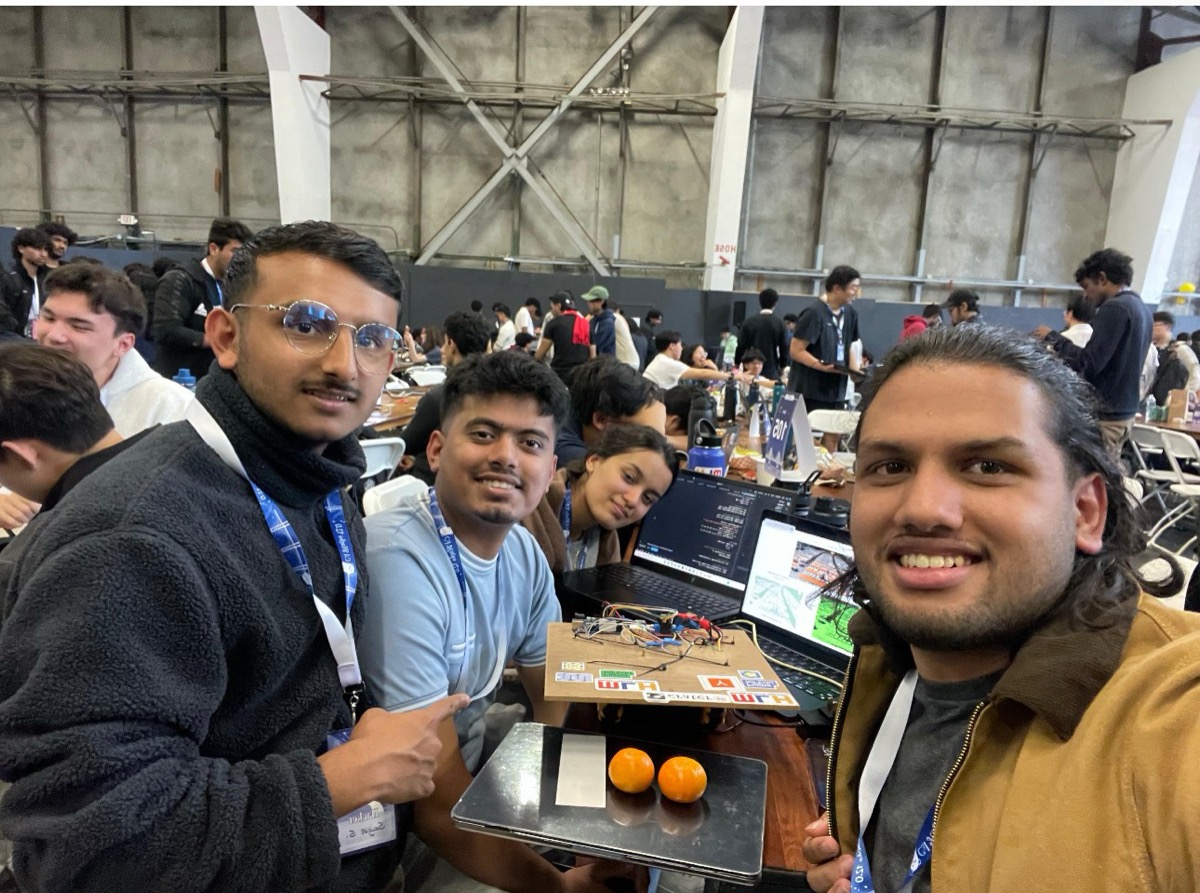 Team Concave selfie at Calhacks'25 with the field robot rig, laptops, and oranges from the ripeness demo