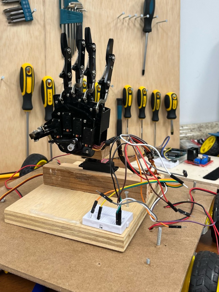 Robotic hand prototype wired to a breadboard on a workbench